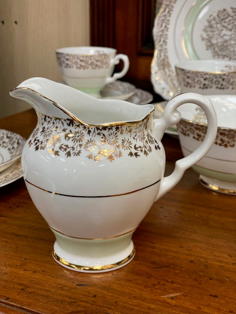 A Tuscan porcelain tea cup and saucer set with matching plates, bowls, and a creamer.